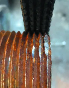 Straightening 1-inch pipe threads using a General Tools thread restoring file. To use the file, align the file with threads, and work from good threads outwards, sothat several of the rows of teeth are always engaged with good threads. Use moderate pressure; enough to keep the file from skipping, but not enough to cut deeply into the pipe or bolt. Take your time. Clean with wire brush when finished.