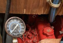 Compression tester set up for testing. The hose is screwed into a glow plug hole after removing a glow plug. Note: This is a mock up to illustrate the tester placement, but this is a tester for a gasoline engine, not a diesel because it only goes up to 300 psi. A diesel tester would go up to 1000 psi. Also, ALL of the glow plugs should be removed, not just one. In addition, the hose is not actually screwed in because the fitting is the wrong size. (Photo/ Phil Decker)