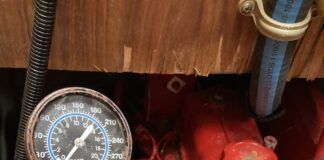 Compression tester set up for testing. The hose is screwed into a glow plug hole after removing a glow plug. Note: This is a mock up to illustrate the tester placement, but this is a tester for a gasoline engine, not a diesel because it only goes up to 300 psi. A diesel tester would go up to 1000 psi. Also, ALL of the glow plugs should be removed, not just one. In addition, the hose is not actually screwed in because the fitting is the wrong size. (Photo/ Phil Decker)