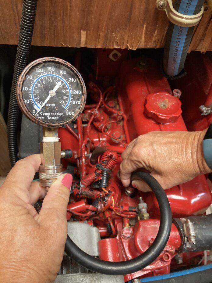 Compression tester set up for testing. The hose is screwed into a glow plug hole after removing a glow plug. Note: This is a mock up to illustrate the tester placement, but this is a tester for a gasoline engine, not a diesel because it only goes up to 300 psi. A diesel tester would go up to 1000 psi. Also, ALL of the glow plugs should be removed, not just one. In addition, the hose is not actually screwed in because the fitting is the wrong size. (Photo/ Phil Decker)