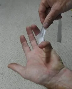 For protecting your overused finger tendons, apply a bracing tape. You can use ½-in. athletic tape, which is available for gym and martial arts use. Here is the tape crossing the first time. (Photo/ Drew Frye)