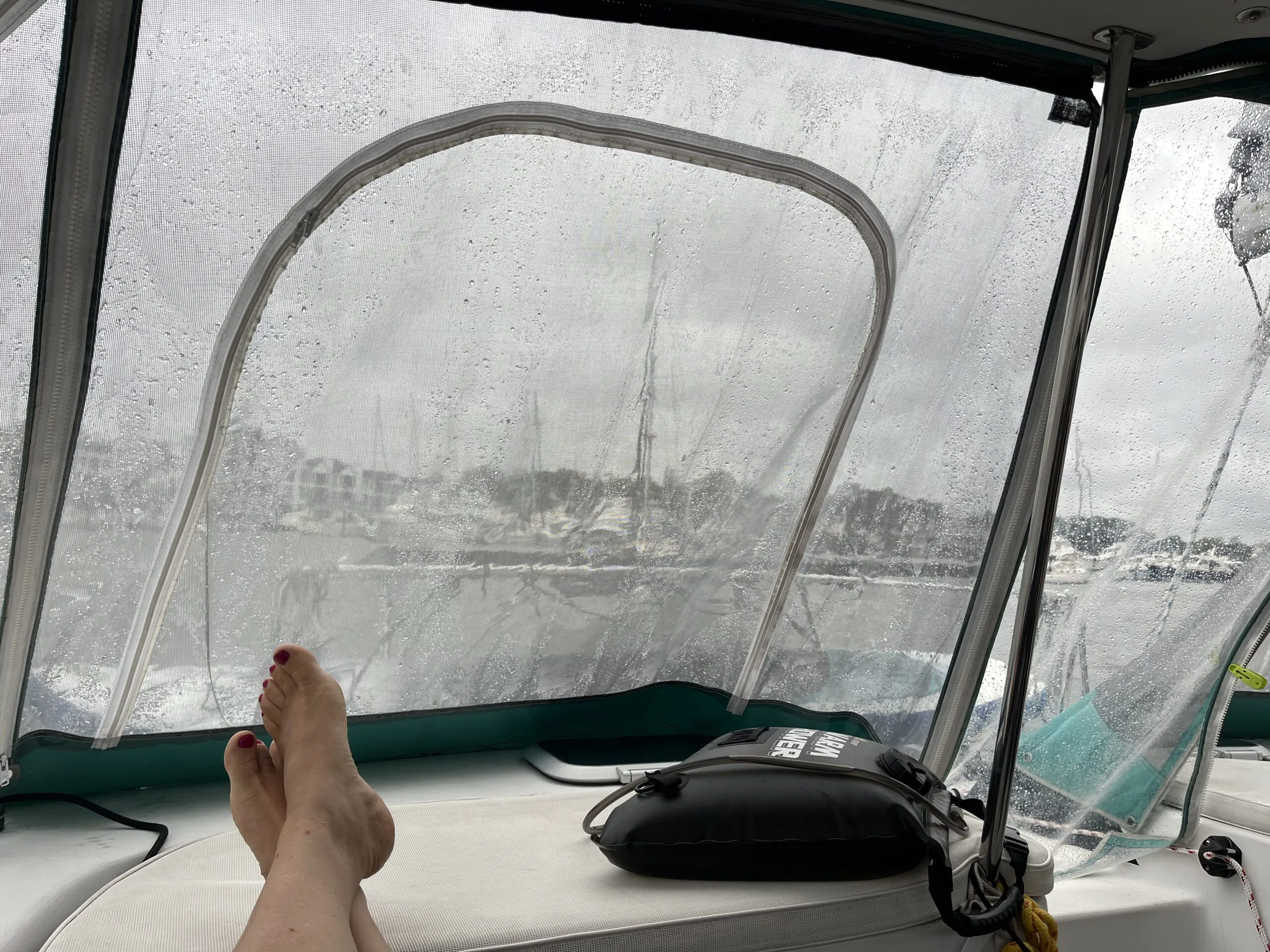 A full vinyl enclosure keeps the cockpit dry on a rainy day. This is the view looking aft from the helm during a rainy day. That solar shower won't be getting very warm today! (Photo/ Alex Jasper)