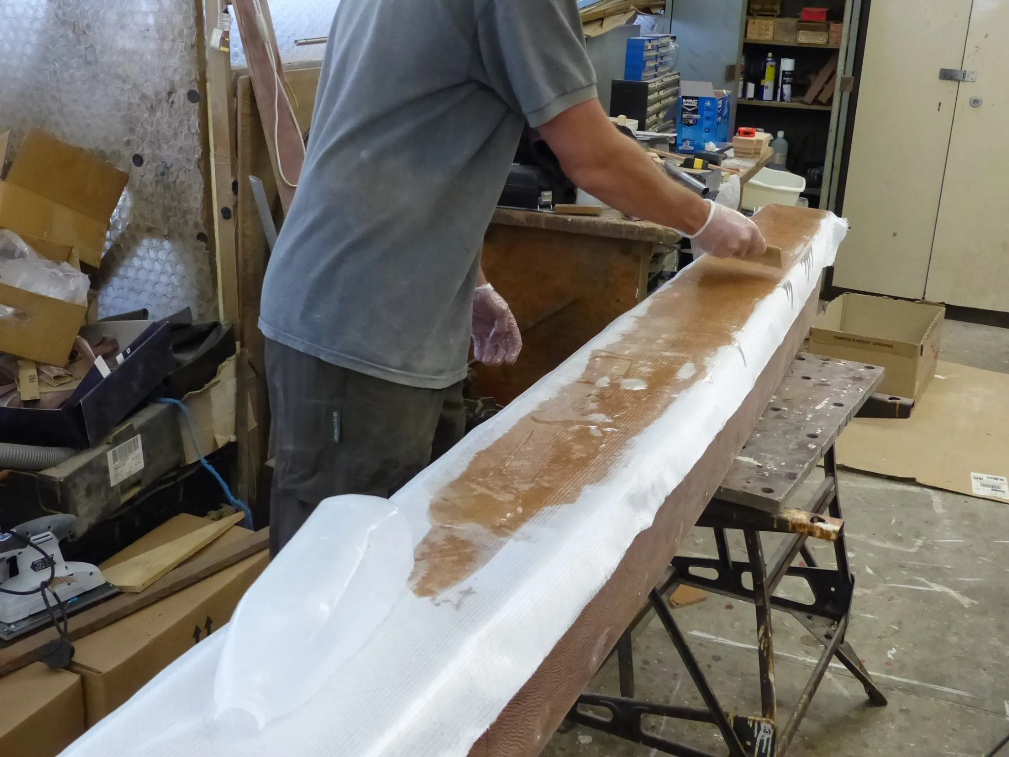 Bi-axial glass cloth is being wetted out, the corners are overlapped for extra strength. (Photo courtesy of Wharram Designs)