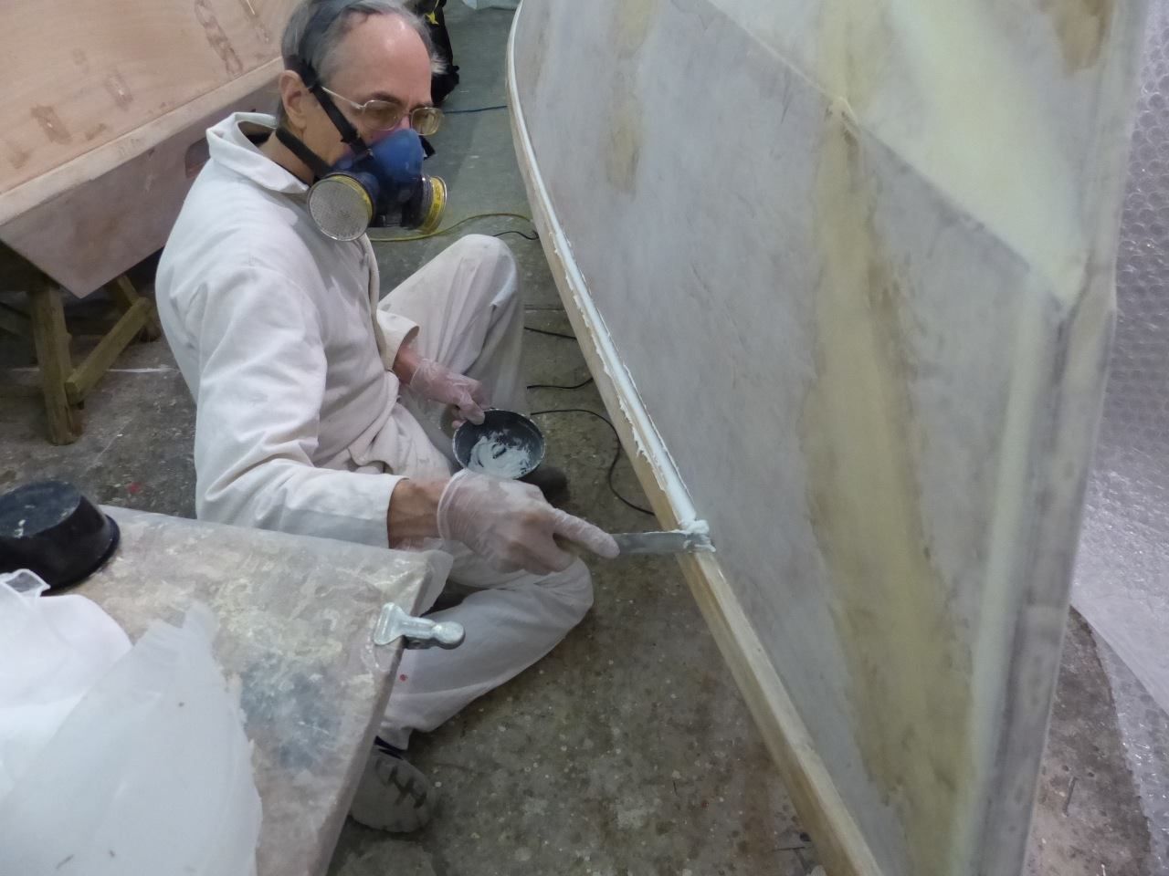 Finally a small fillet is made over the glass joint under the gunnel. You can also see some final fairing over the glass joints made with a thicker mix of epoxy resin plus Microlight filler applied with wide putty knife and trowel. (Photo/ Wharram Designs)