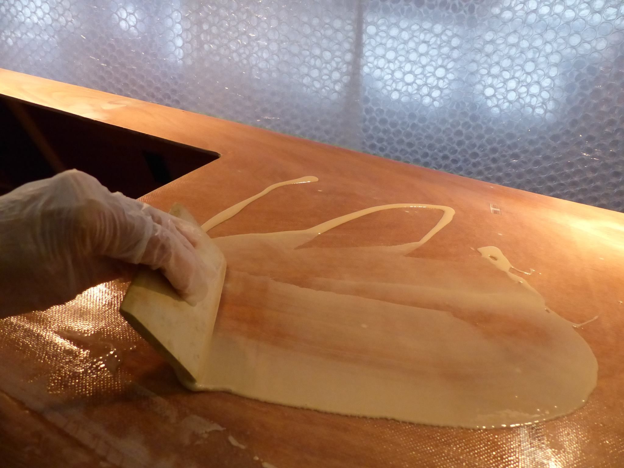 Spreading the resin with a squeegee on the large flat surfaces. (Photo/ Wharram Designs)