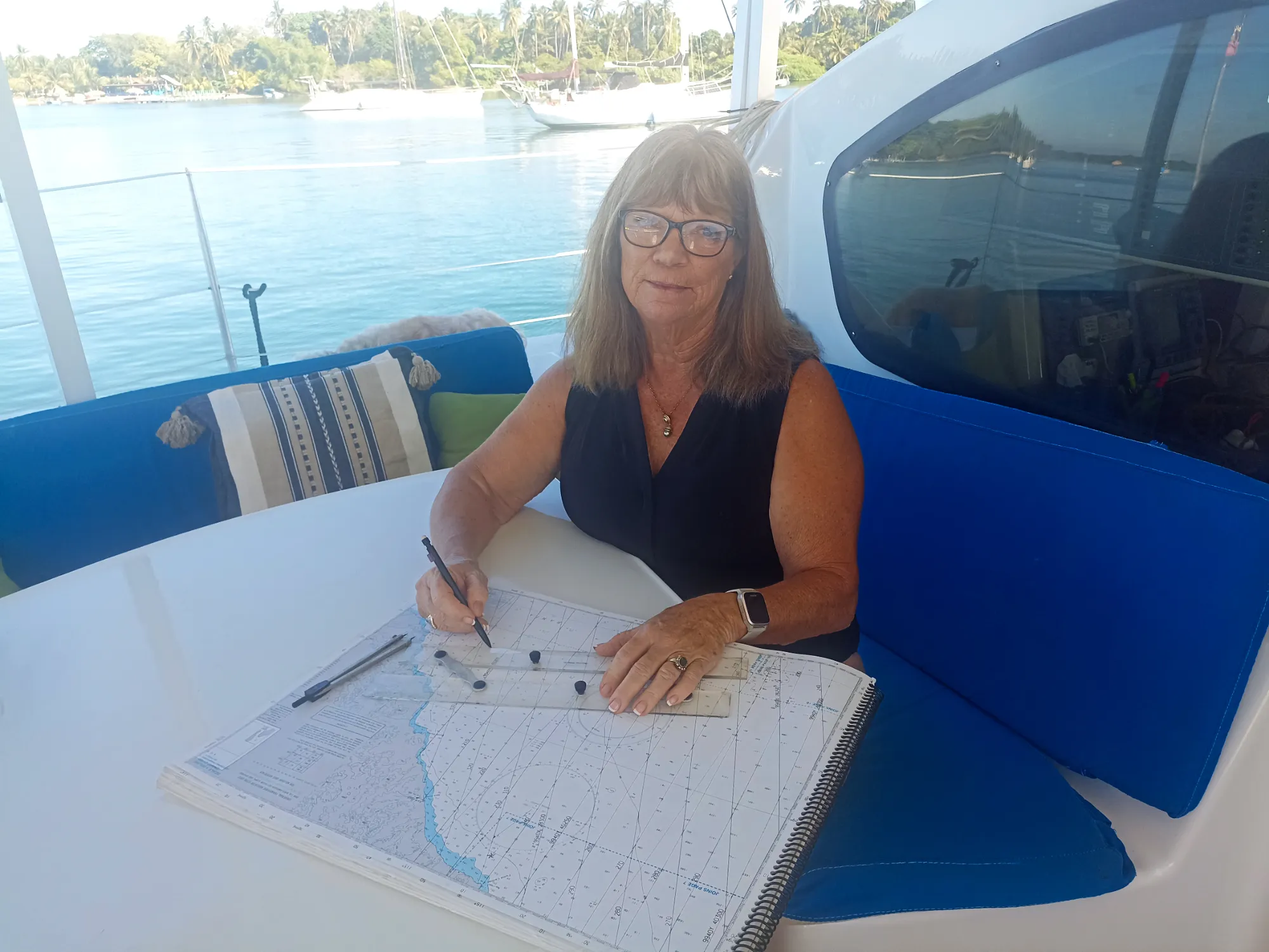 Pamela with her paper charts and parallel rulers, essential tools to navigate via the dead reckoning protocol. (Photo/ Pamela Bendall)