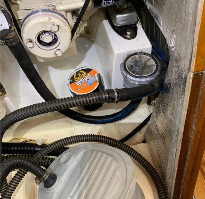The dinghy pump connected to the raw water hose removed from the strainer, ready to blow air back through the saildrive leg, ready to be taped. (Photo/ Bert Vermeer)