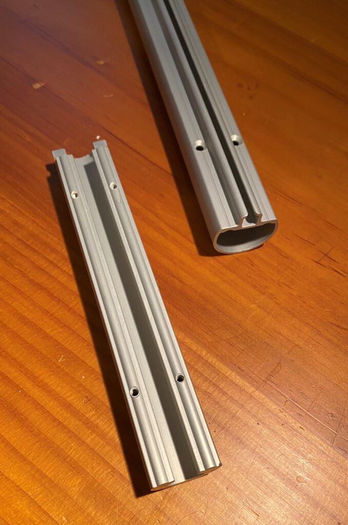 A rigid metal extrusion from a Harken MKIV Unit 0 furling system, top right, along with a connector. The metal sections are screwed together using tiny machine screws (with thread locking fluid) and plastic bushings that protect the forestay from wear. (Photo/ Doug Henschen)