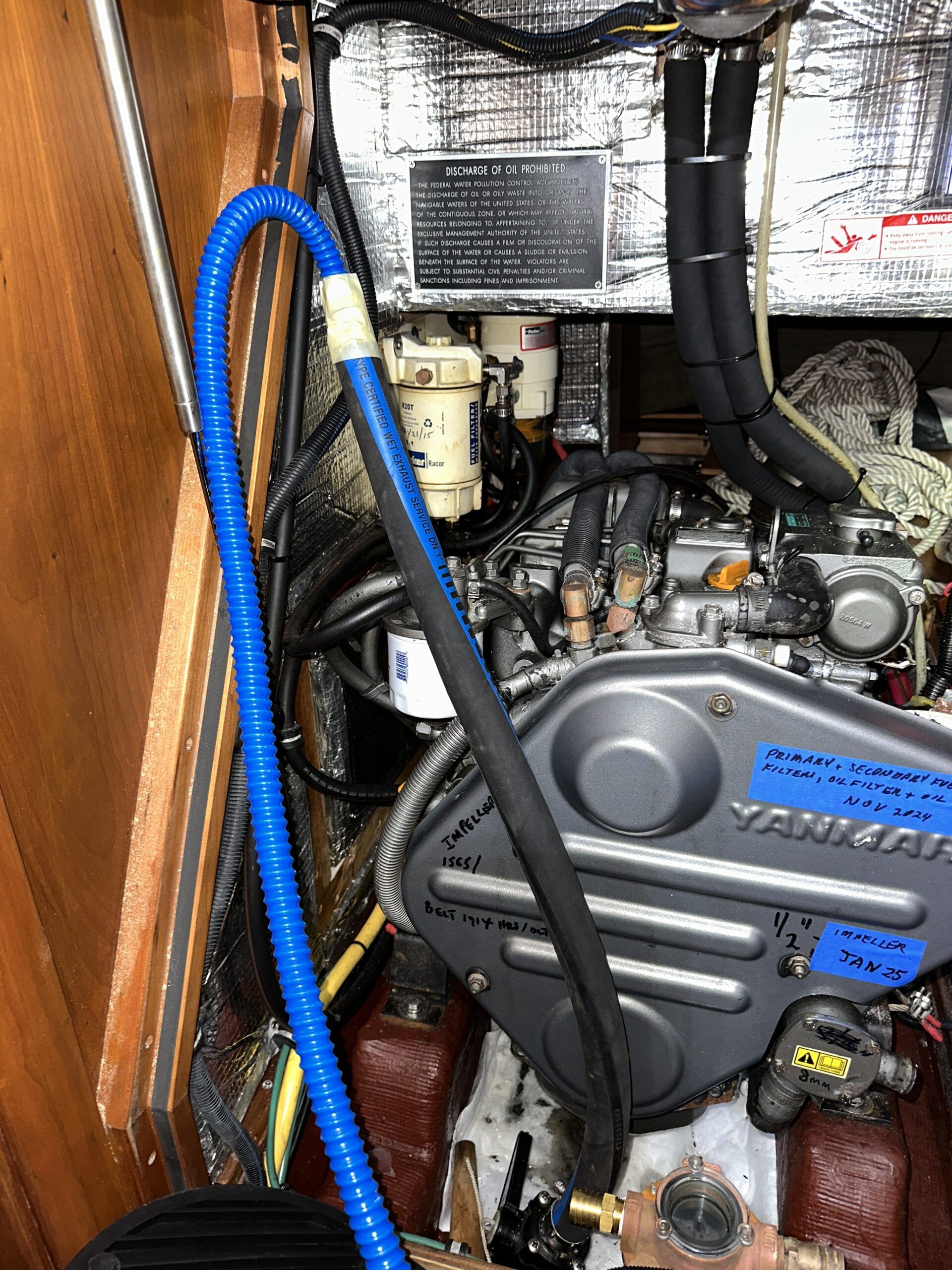 The replacement hardwall hose is in place on the seacock hose barb and naturally wants to remain in a straight line. I've attached the dinghy bellows foot pump to the hose to demonstrate to the owner that the set-up would work to clear a blockage. The straight hose barb is attached to the sea strainer visible at the bottom. (Photo/ Bert Vermeer)