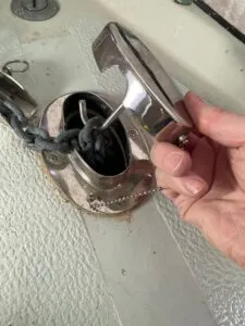 A hawse pipe and chain lock installed on the author’s Albin Ballad 30. A retaining chain keeps the pipe cover from going over the side while a hook employs the weight of the chain to keep the cover secured over the pipe. (Photo/ Doug Henschen)