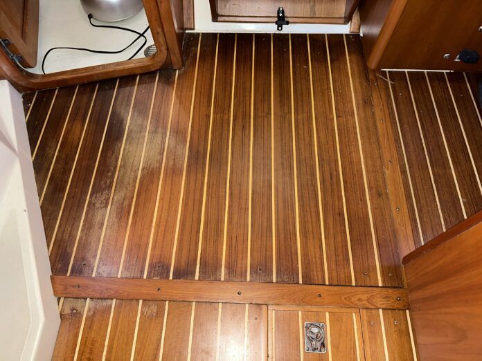 The cabin sole with water damage, looking aft towards the companionway from the salon. The new damage is on the left, while the old damage is near the doorway at the top of the photo. (Photo/ Bert Vermeer)