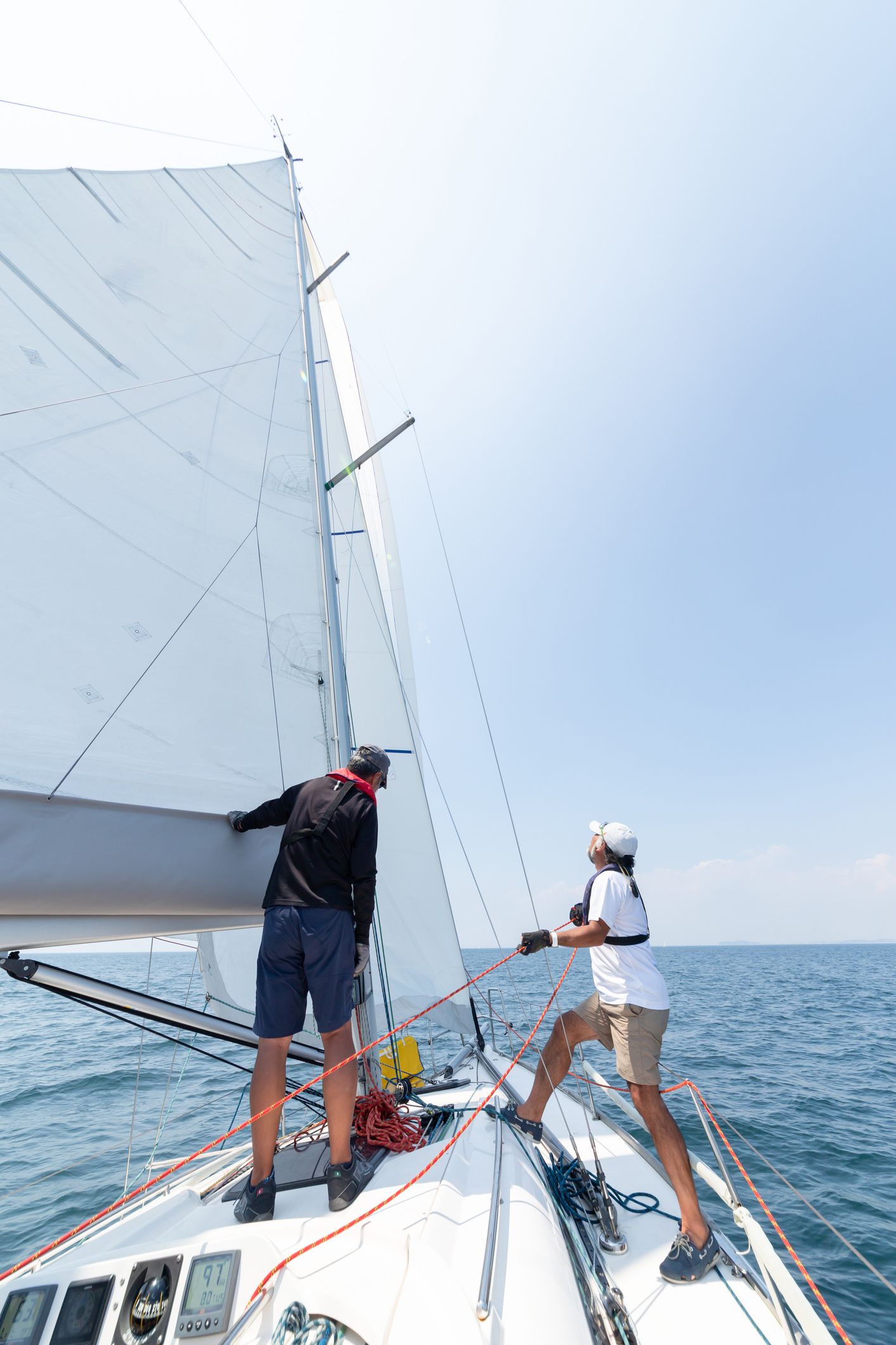 These sailors are wearing lifejackets and have proper footwear. Even though the sailor is focused on the sail trim, they also have their feet placed to brace for a potential heel. 