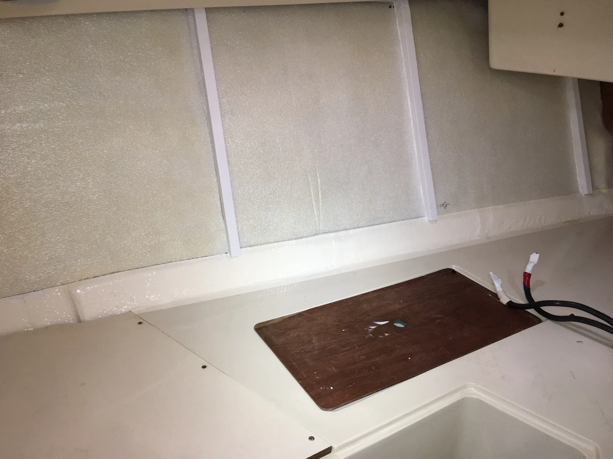 The closed cell ½” foam glued into place with contact cement. Note that the bottom edge, not to be covered with the oak strips, has been finished in the same color as the original gelcoat and wood. (Photo/ Bert Vermeer)