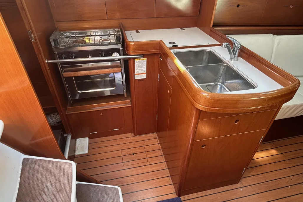 The L-shaped galley features a two-burner stove, double sink, and enclosed storage with teak doors. Photo courtesy of YachtWorld.com
