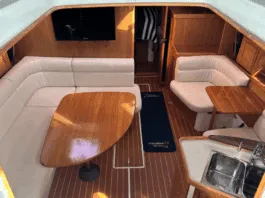Warm varnished teak and solid wood doors create a space that feels substantial without being dark. The convertible furniture tries to solve the age-old problem of making one space do everything. Courtesy of Yachtworld.com