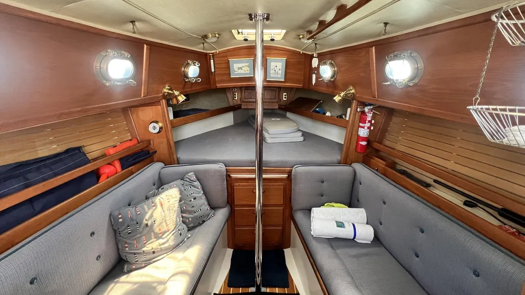 Hand-rubbed oiled teak surfaces, bronze ports and the absence of a forward bulkhead creates surprising spaciousness. Courtesy of Yachtworld.com