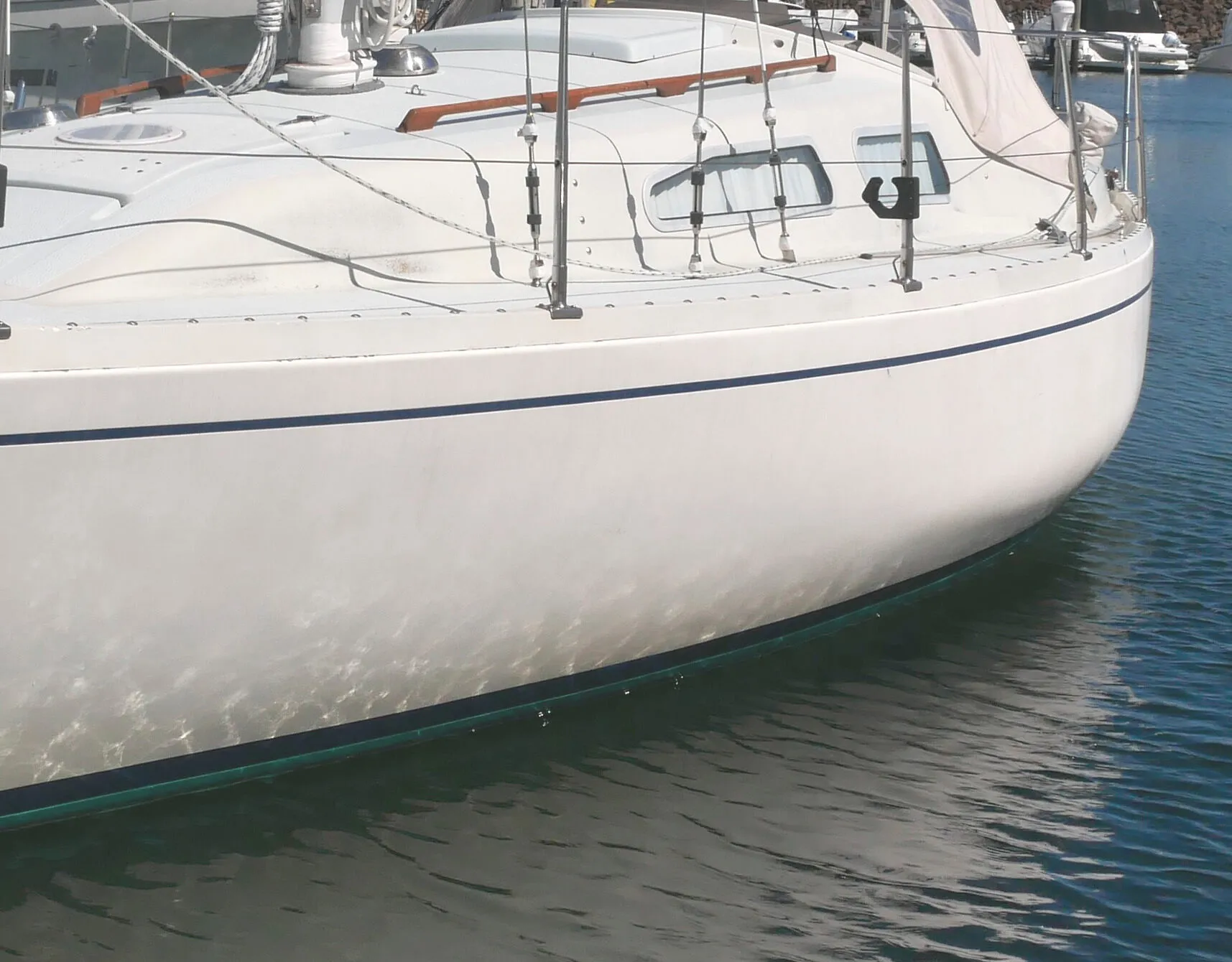The Ballad’s knuckle-shaped hull profile amidships moves the center of buoyancy outboard and helps the boat stand up to the wind. Visible atop the 2-in. high toe rail are the rounded heads of stainless bolts that hold the hull-deck joint together. Port and starboard sail tracks curve inward, toward the stays, as you move the sheet lead cars forward. (Photo: Doug Henschen)