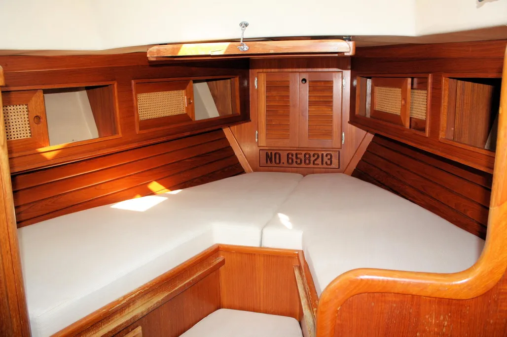 The V-berth, with its mahogany-trimmed walls and storage locker overhead, shows Bristol's traditional joinery at work. Headroom drops to around 6 ft. Courtesy of YachtWorld.com