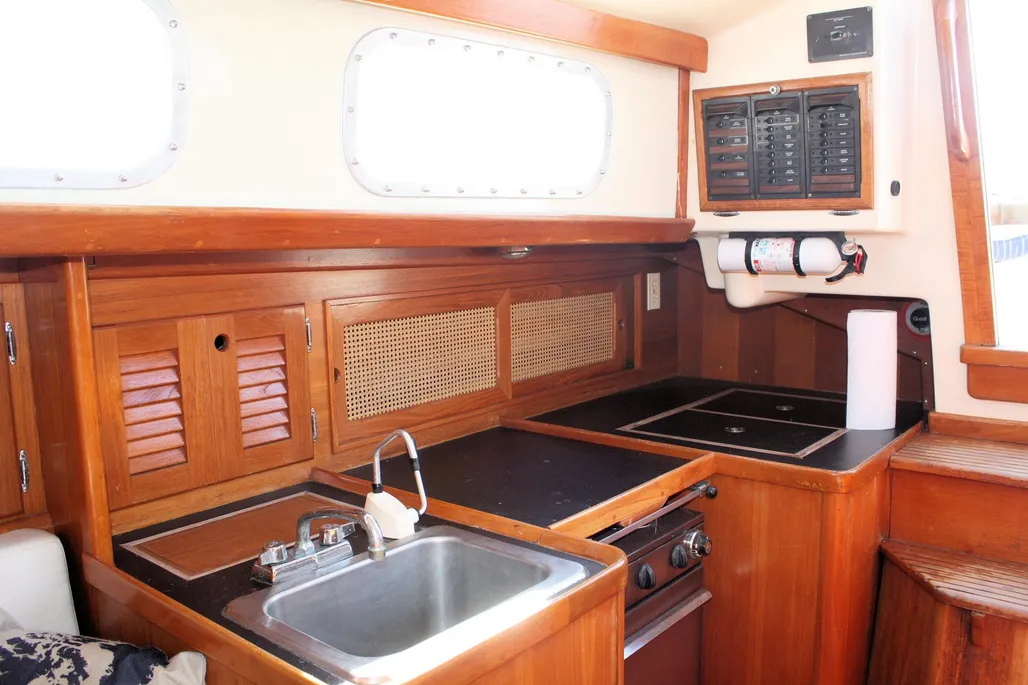 The aft galley arrangement varies by configuration: boats with nav stations have a compact starboard galley, while those without feature a more spacious port-side layout with opposite icebox. Courtesy of YachtWorld.com