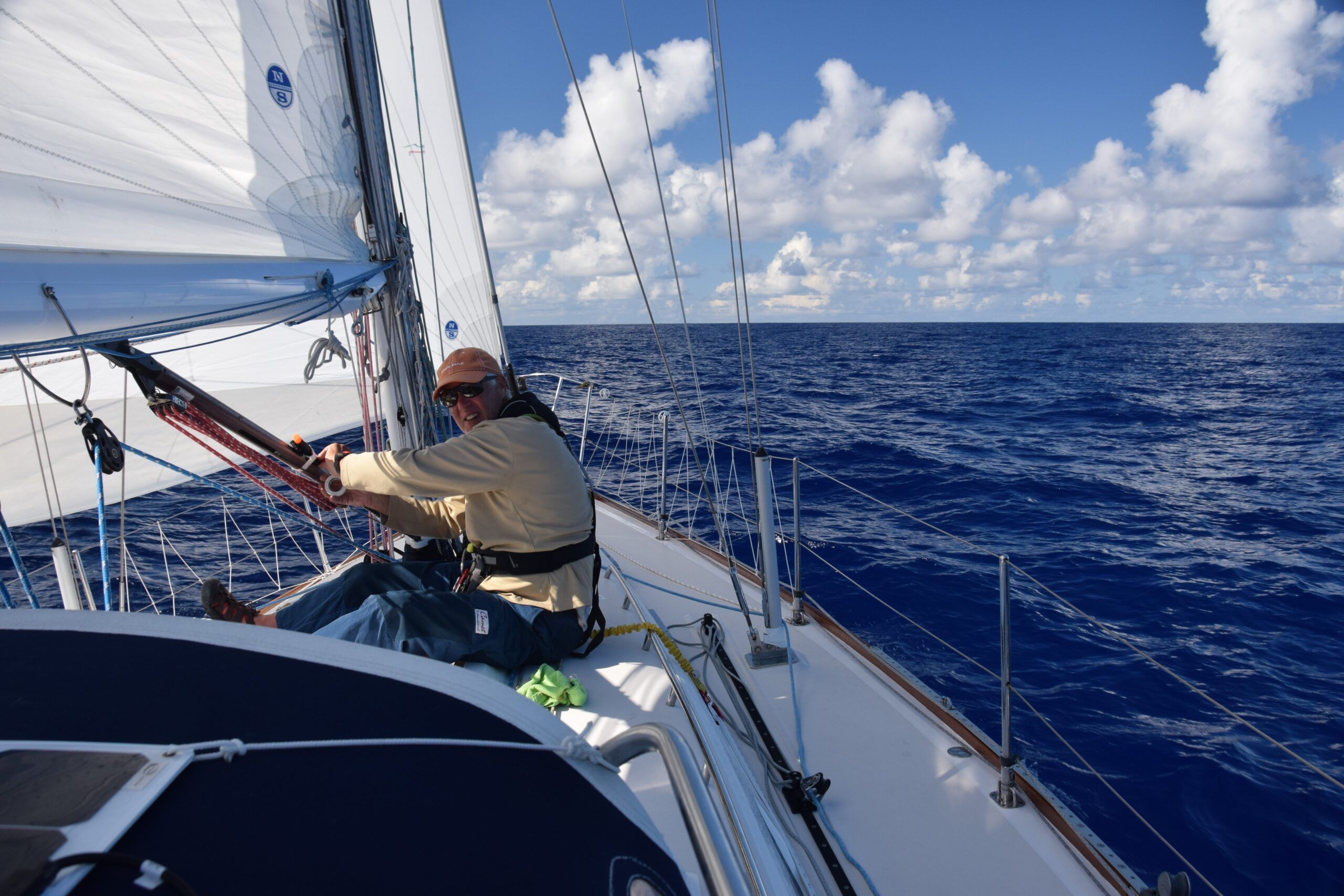 Chris on the cabin top adjusting the boom vang control lines, properly tied onto the safety line. (Photo/ Bert Vermeer)