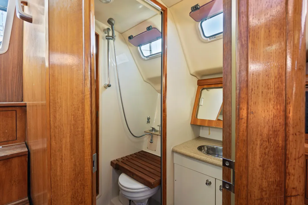 The single head is divided into two compartments accessible from both the main cabin and aft stateroom. The separate shower stall measures 24 in. x 45 in. and is enclosed by a door, allowing simultaneous use of the vanity-toilet area and shower—a practical arrangement with 6-ft. 2-in. standing headroom throughout. Courtesy of Yachtworld.com
