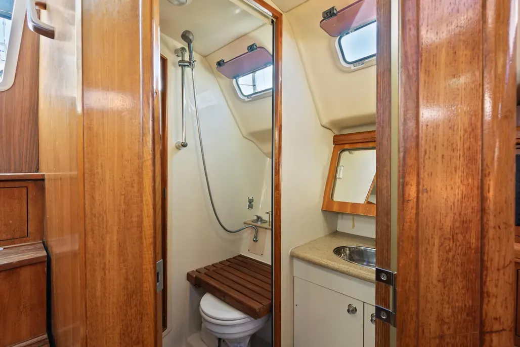 The single head is divided into two compartments accessible from both the main cabin and aft stateroom. The separate shower stall measures 24 in. x 45 in. and is enclosed by a door, allowing simultaneous use of the vanity-toilet area and shower—a practical arrangement with 6-ft. 2-in. standing headroom throughout. Courtesy of Yachtworld.com