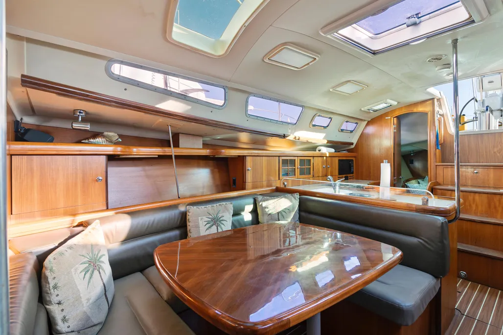 The main saloon features U-shaped settees around a teak dining table with generous headroom and natural light from deck hatches and hull ports. The low-maintenance Everwear laminate sole replaced traditional teak and holly. Courtesy of YachtWorld.com