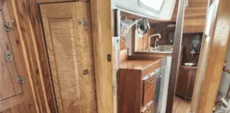 The companionway and main cabin entrance showcases classic teak joinery throughout, with abundant storage lockers, a spacious galley to starboard, and traditional teak-and-holly sole. The deep companionway sill provides a secure threshold for offshore passages. Courtesy of SailboatListings.com