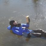 Reading Isaac Asimov. To demonstrate humorously, but also accurately, that I spent considerable time in ice water for the test. It was as comfortable like a water bed and reading helped pass the time. In between I performed climbing, jumping, and boarding tests, as required by the immersion suit standard. I swam around the harbor a little bit, because I could and because with some ice on the water, there was zero traffic. (Photo/ Drew Frye)