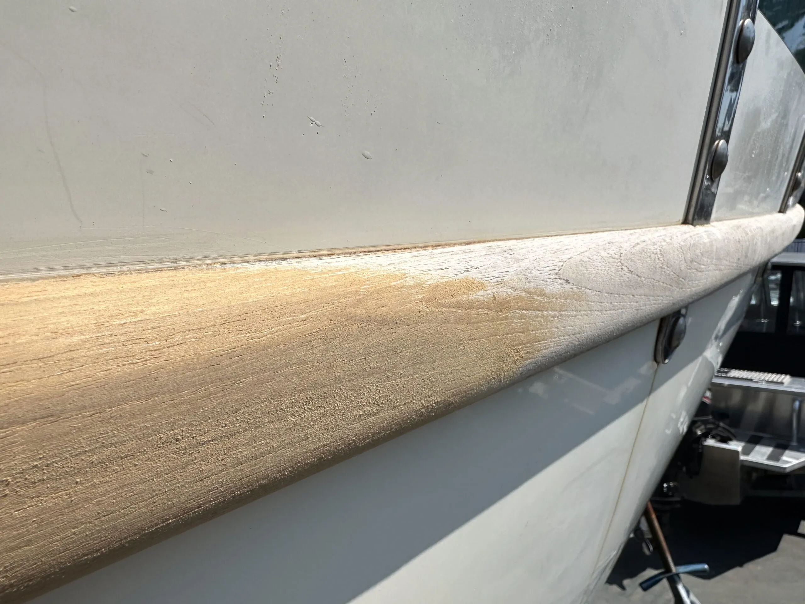 Weathered rub rail on a Pacific Seacraft 37—sanding has begun. (Photo/ Bert Vermeer)