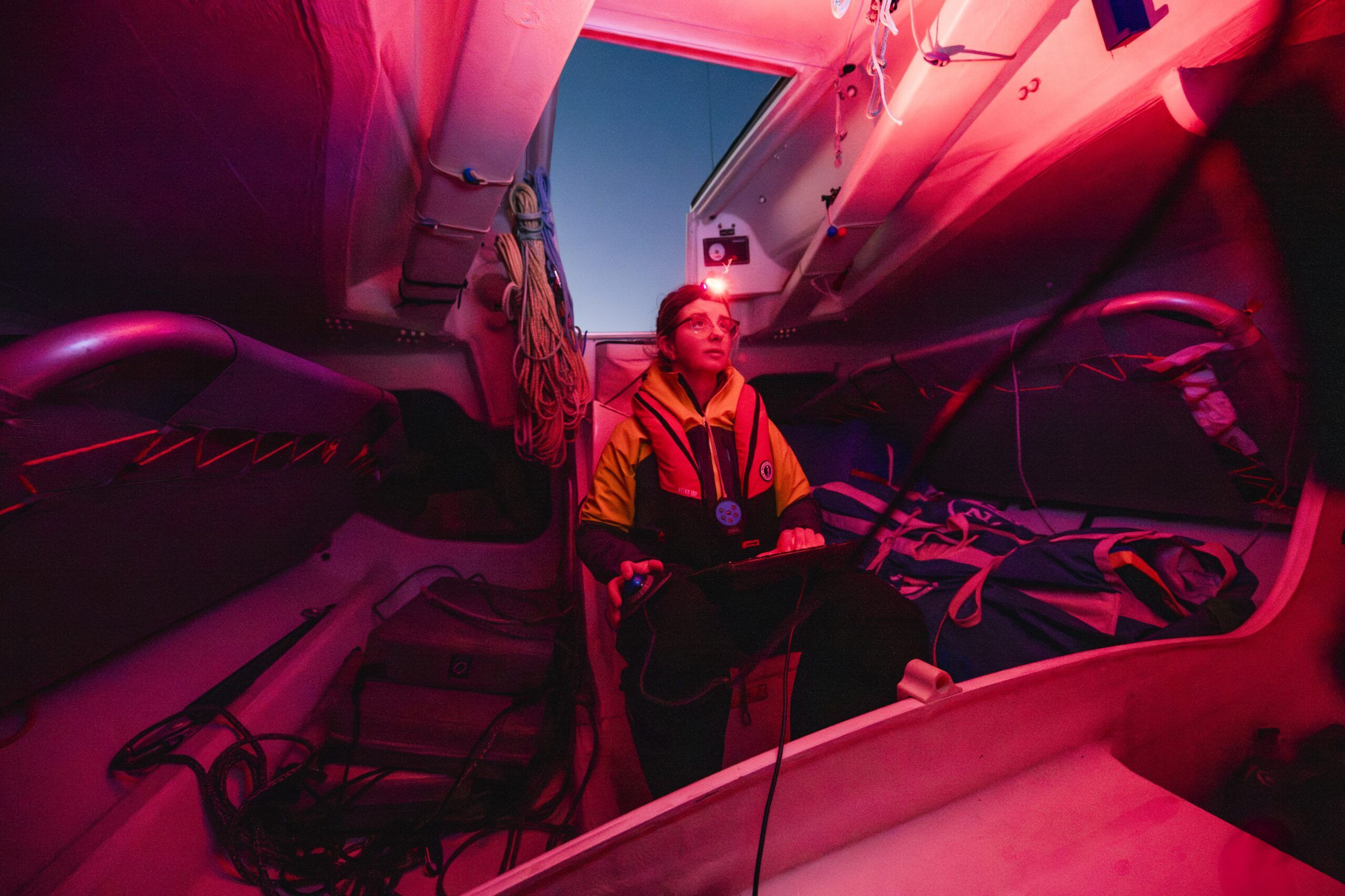 Erica familiarizing herself with the nav station in low light. (Photo/ <a href=“https://www.catebrownphoto.com/-/galleries/portfolios/sail”>Cate Brown Photography</a>)