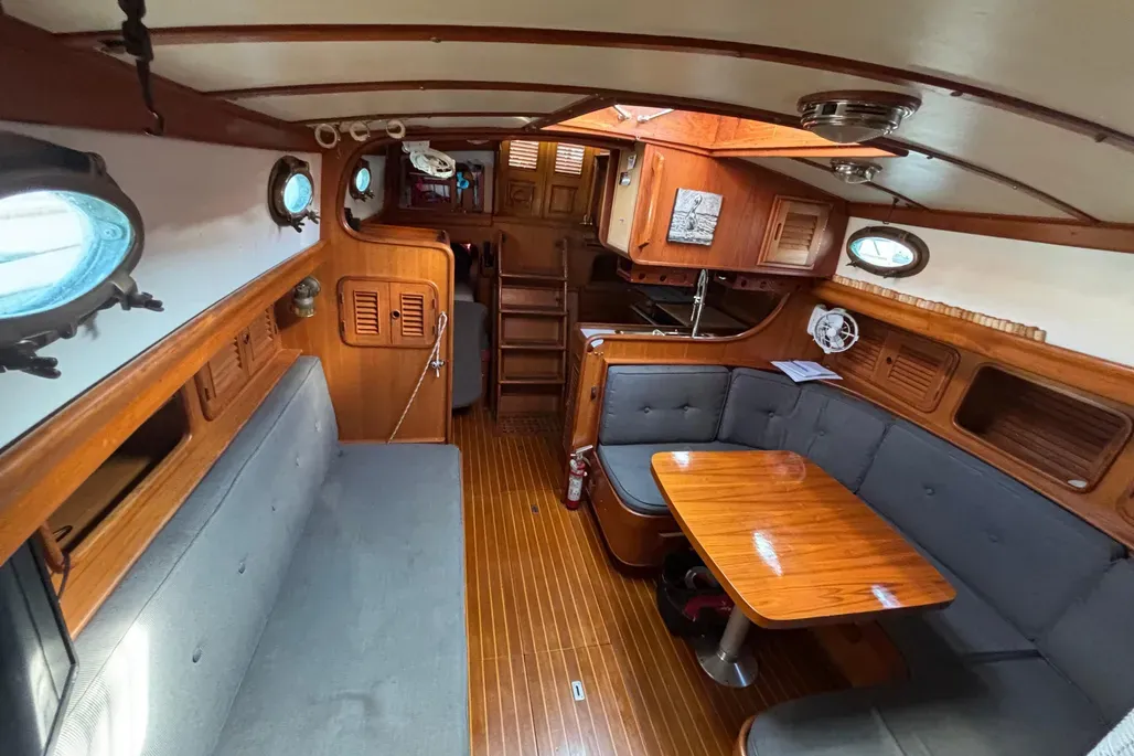 The settee pulls out to form a sea berth, while the pilot berth—often called the "pile-it berth"—hides above it. Ample storage behind and beneath the dinette seats keeps gear stowed on long passages. (Photo courtesy of YachtWorld.com)