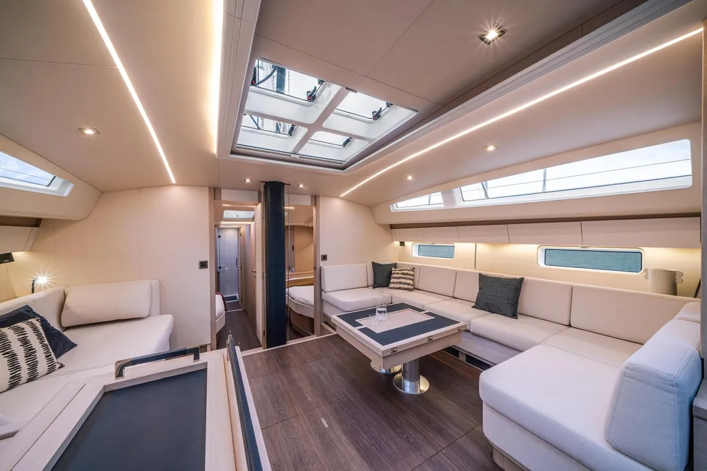 The raised saloon features U-shaped seating and a powered folding table that seats six or more, with abundant natural light flooding in from overhead hatches and cabin top side windows.(Photo courtesy of YachtWorld.com)
