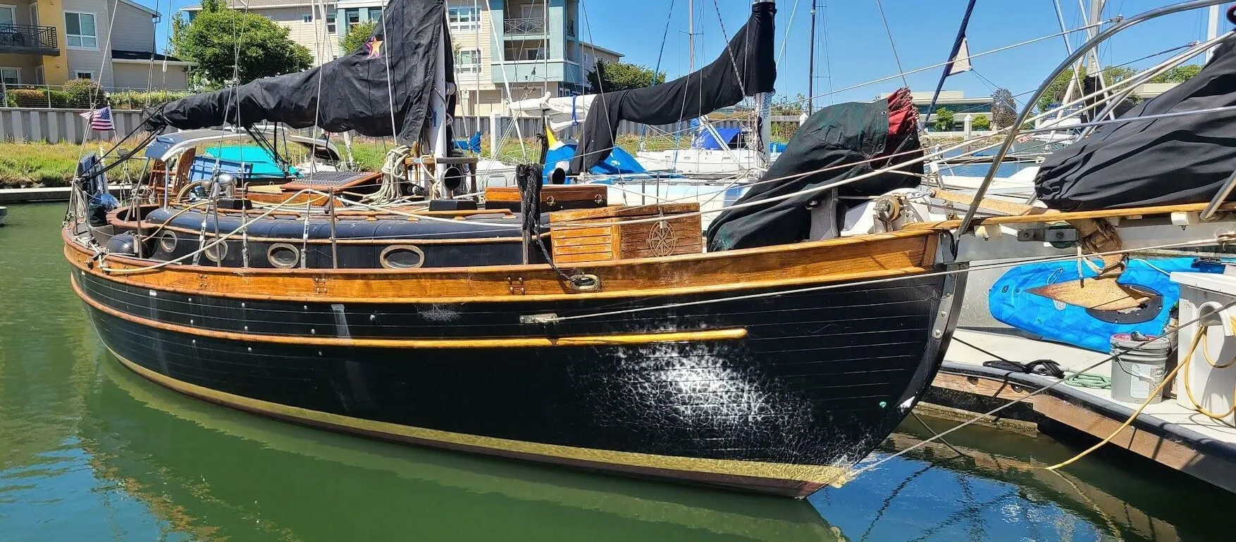 From abeam, the Union 36’s double-ended hull shows the heavy sheer, tall bulwarks and oval bronze ports that define her “tank trimmed in teak” look. The full-length rubrail and thick cap rail protect the topsides but also add to the brightwork workload owners must manage. (Photo/ Seattle Yachts)
