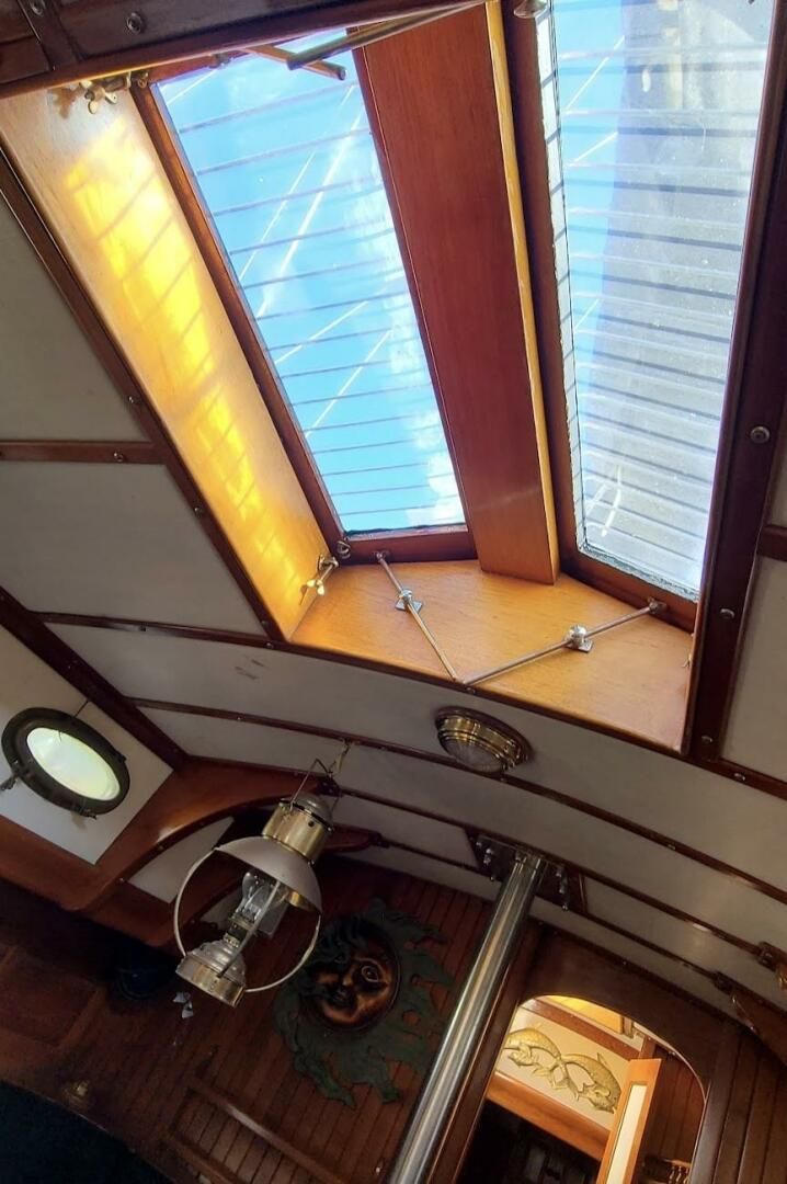 The main-cabin butterfly hatch, reinforced with stainless-steel rod, floods the saloon with light. An oval bronze port and gimbaled brass lamp are hallmarks of the Union 36's traditional interior. (Photo/ Seattle Yachts)
