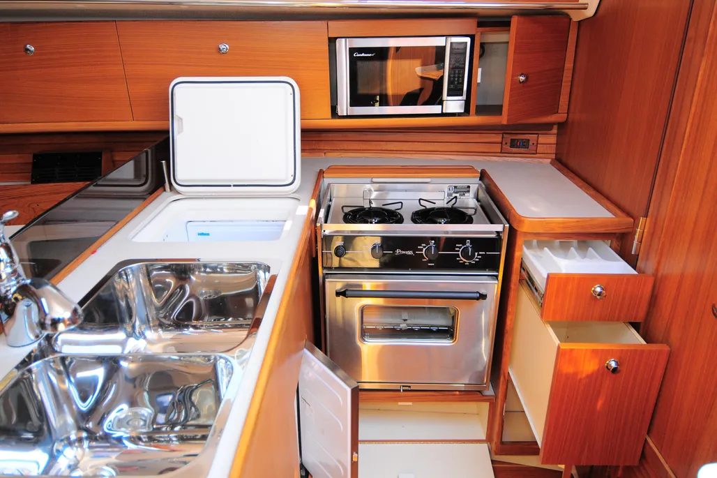 The U-shaped galley to starboard is seagoing in shape and size, with a deep centerline double sink, top-loading fridge/freezer and enough locker space to keep a small crew well fed underway. (Photo courtesy of Yacht World)