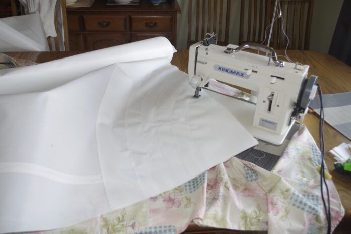 Sewing the patches. For the head and tack stick all the patches together with the double-sided tape then stick the complete assembly to the sail. Now run a single row of stitches along the edge of each patch and a double row on the largest one. It is hard to see where the edges of the patches are. Using bright light behind the sail will show them up then mark the edge with a soft pencil to guide your stitching. The other issue is that at this point you have at least half the sail put together and that is difficult to maneuver. I found it easier to put the machine on a couple of pads so that I could swing the machine rather than having to move the sail.