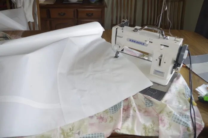 Sewing the patches. For the head and tack stick all the patches together with the double-sided tape then stick the complete assembly to the sail. Now run a single row of stitches along the edge of each patch and a double row on the largest one. It is hard to see where the edges of the patches are. Using bright light behind the sail will show them up then mark the edge with a soft pencil to guide your stitching. The other issue is that at this point you have at least half the sail put together and that is difficult to maneuver. I found it easier to put the machine on a couple of pads so that I could swing the machine rather than having to move the sail.
