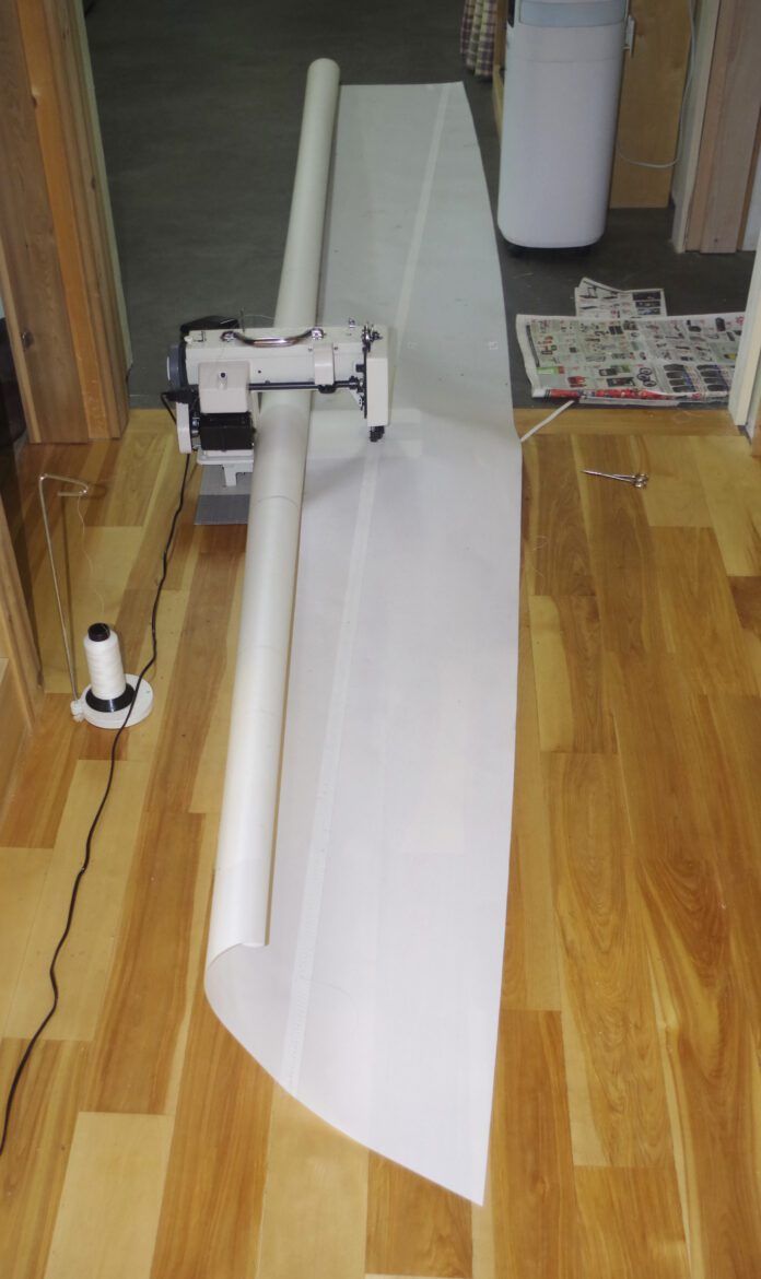 When sewing wider seams you need to work in the floor. A hard floor is ideal as it allows the sail to move easily. On carpet, you will need a steady push as the machine will not be able to pull the cloth through and your stich length will come out too short. Here I am sewing the foot piece which is the longest cross seam. You need a clear space twice the length of the seam.
